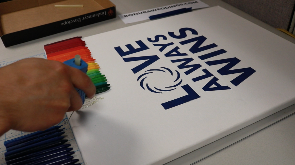 Our Creative Director David preparing our #LoveAlwaysWins sign by pasting Crayola crayons to the top after hand cutting our stencils